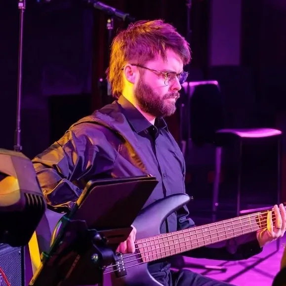Alex playing bass guitar on stage